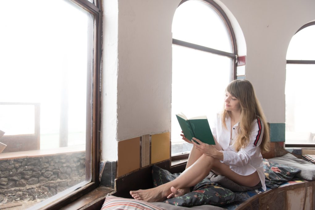 Woman reading book near window