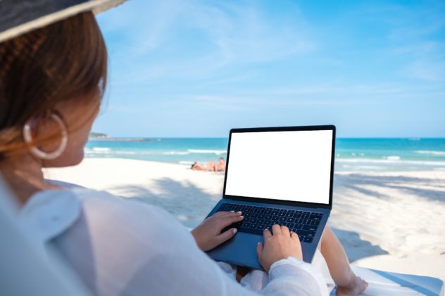 a woman using and typing on laptop computer with blank desktop screen on the beach, improve writing speed